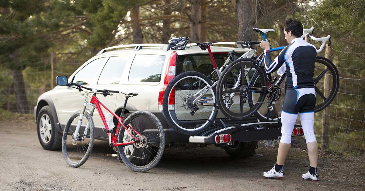Cyclist fitting bike on bike rack of an estate car