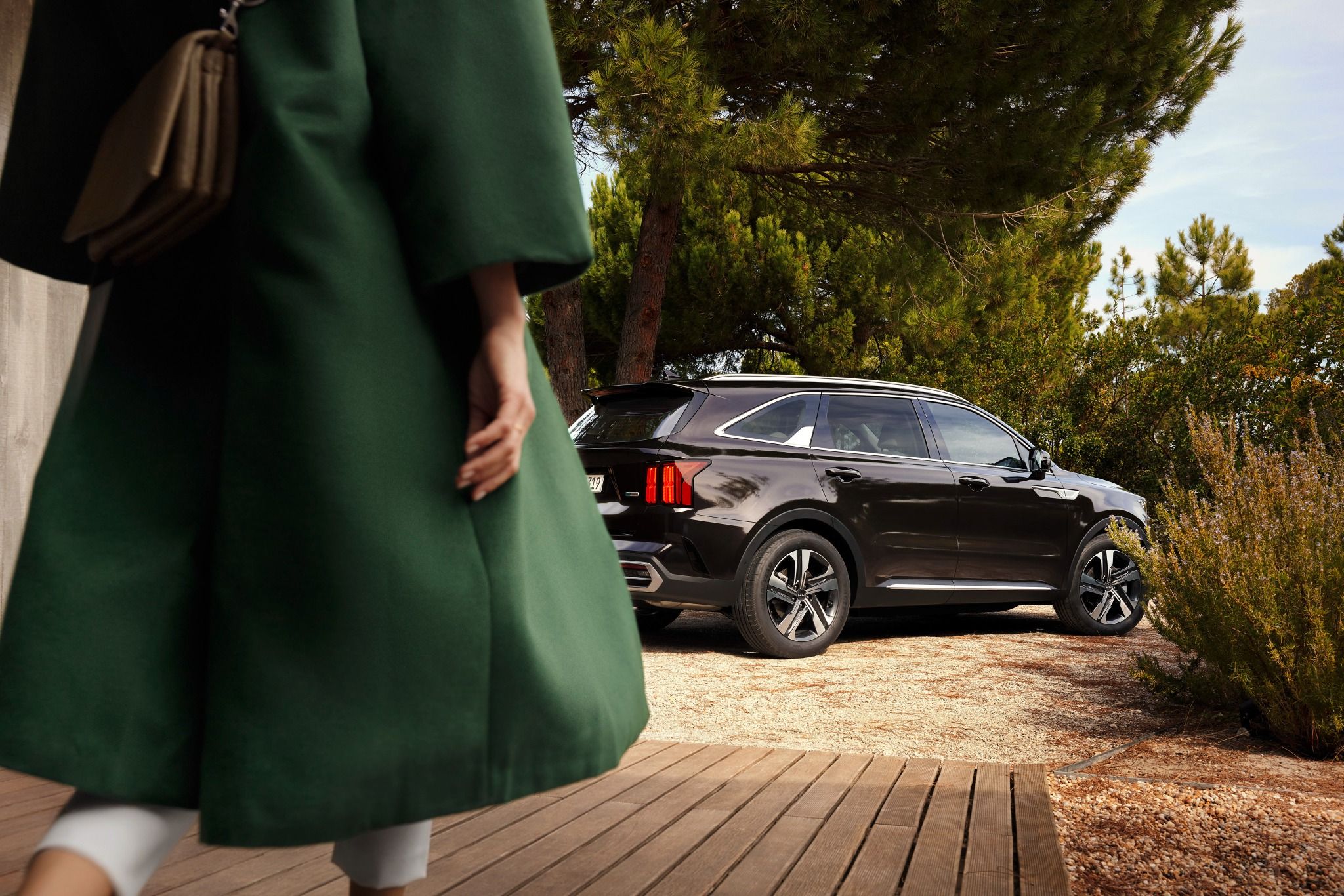 Woman with a green coat walking to a kia sorento