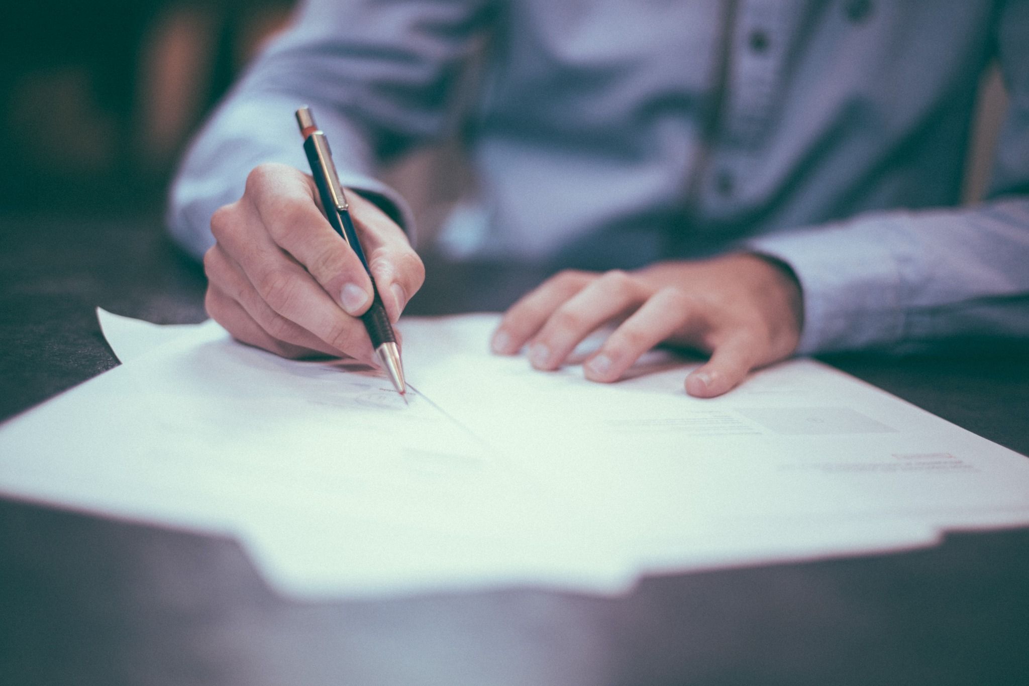 Man Holding a Pen to a Piece of Paper