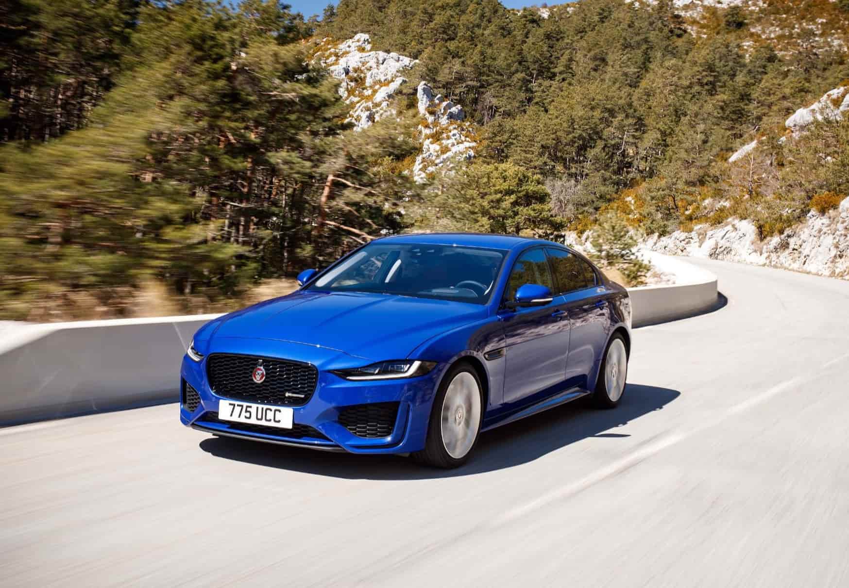 Blue Jaguar XE driving down coastal road