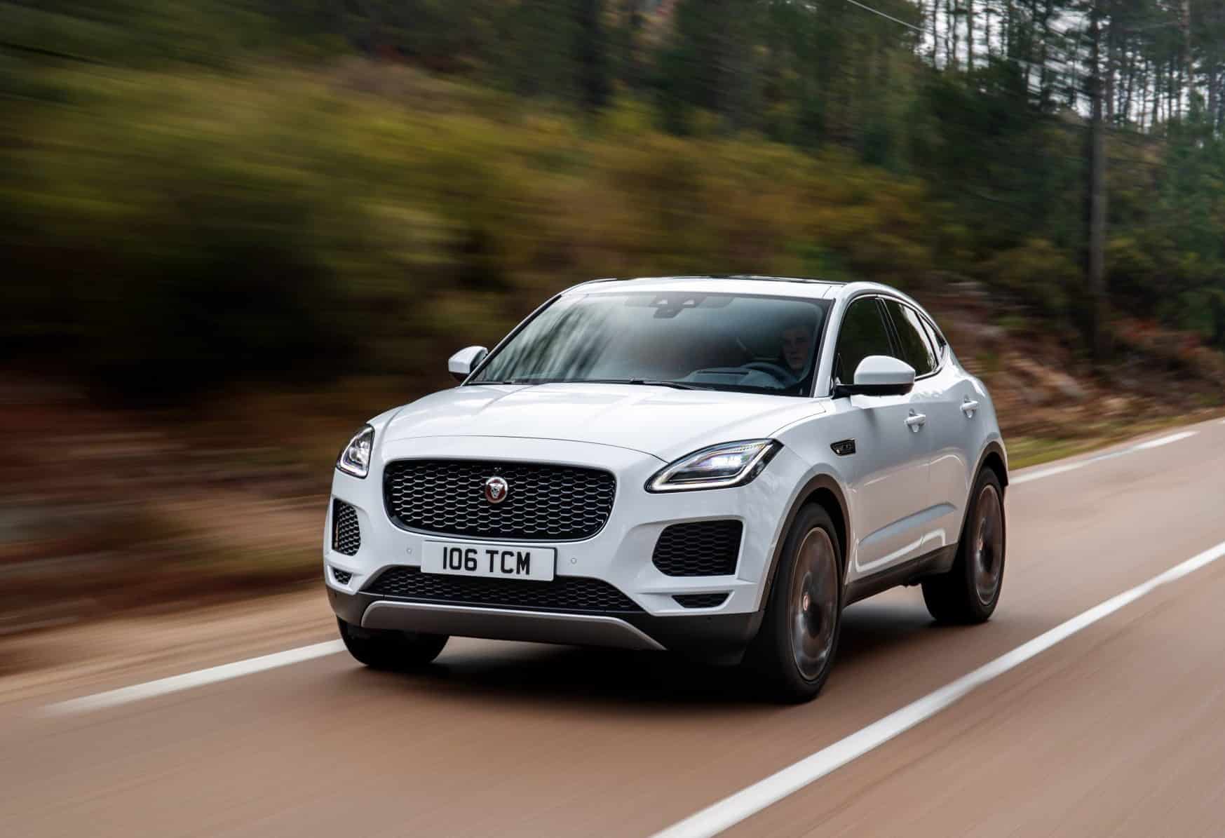 white jaguar e pace driving down a  road