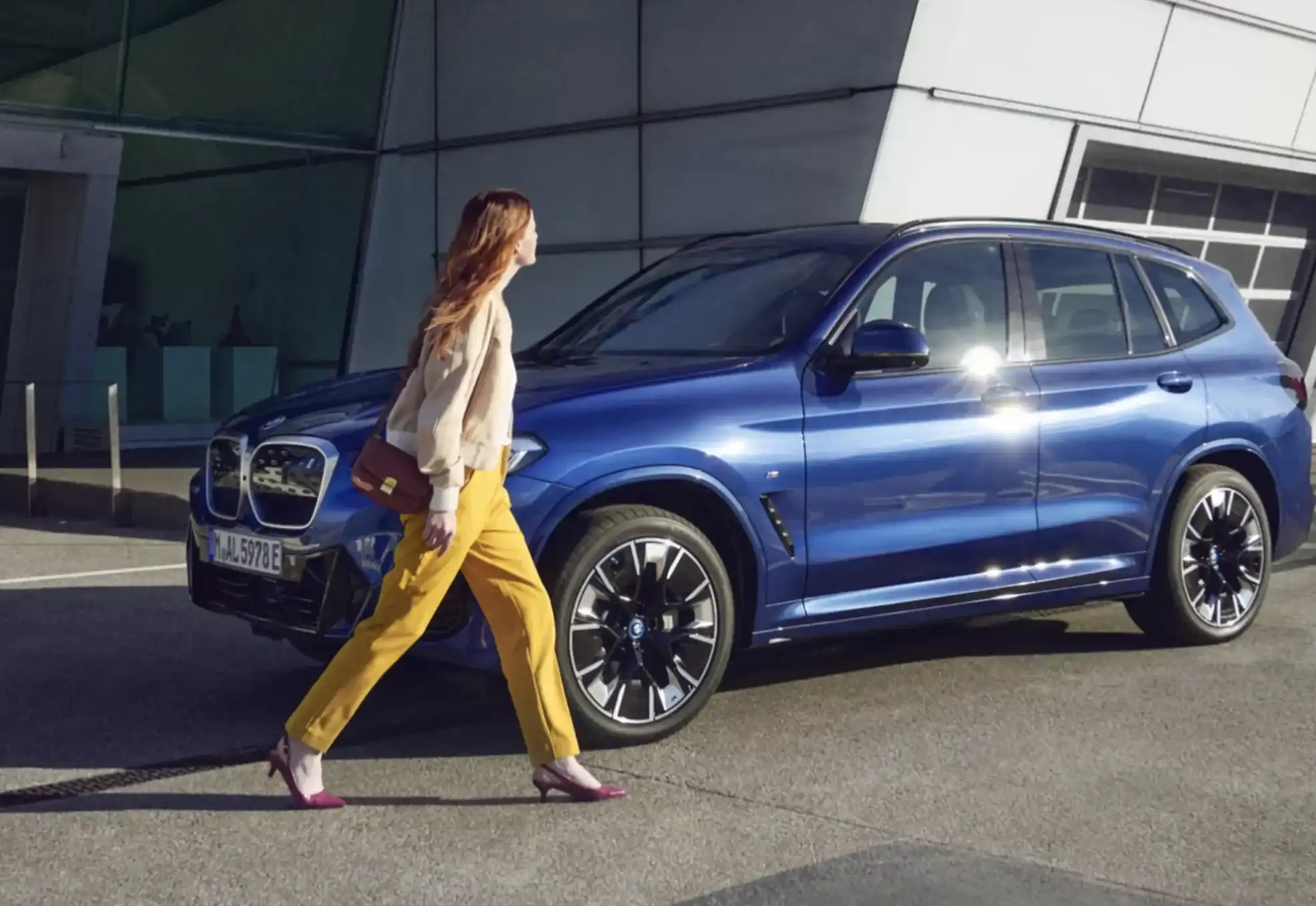 Blue BMW with woman walking next to it