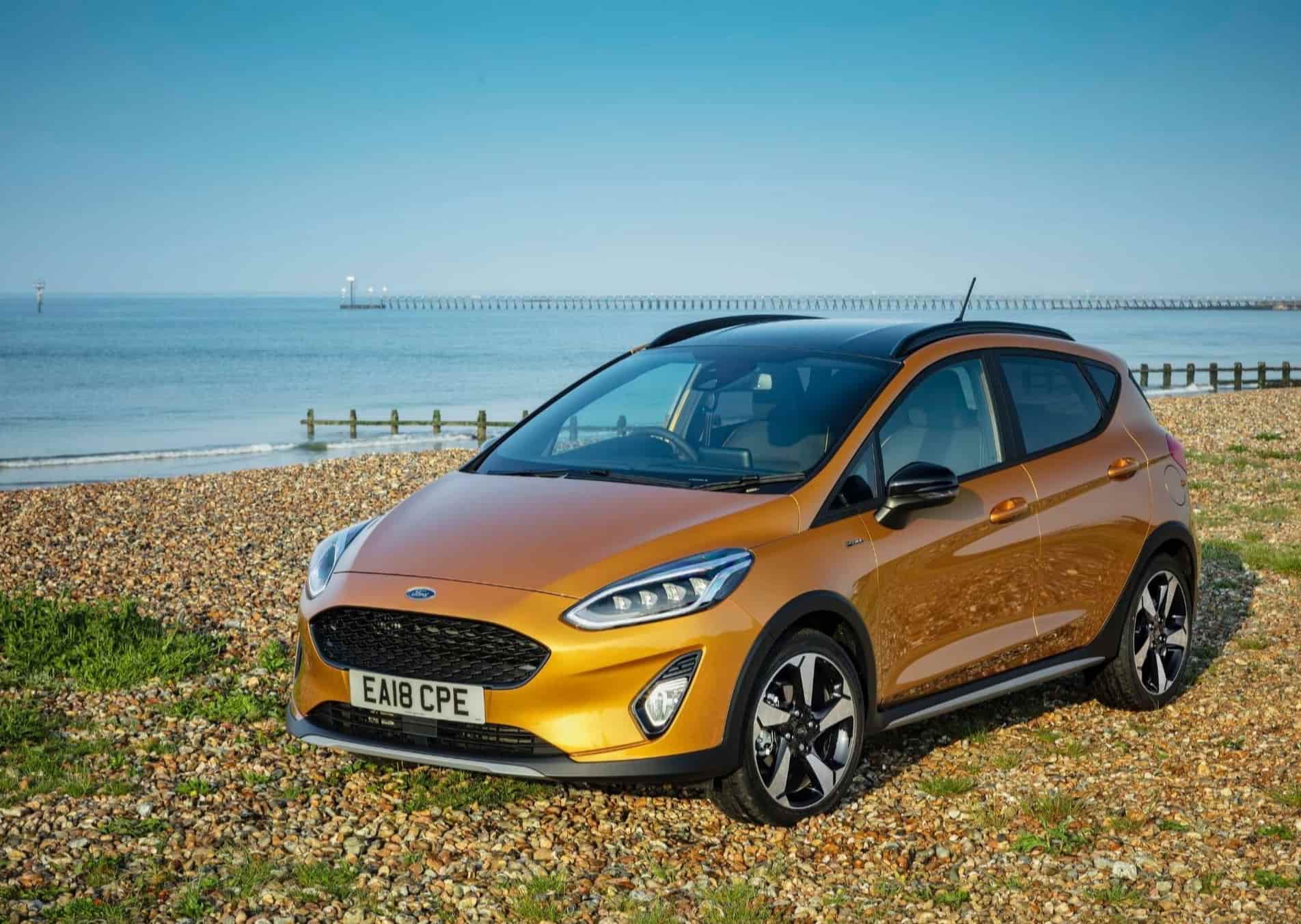 Orange fiesta parked on grass in front of the sea