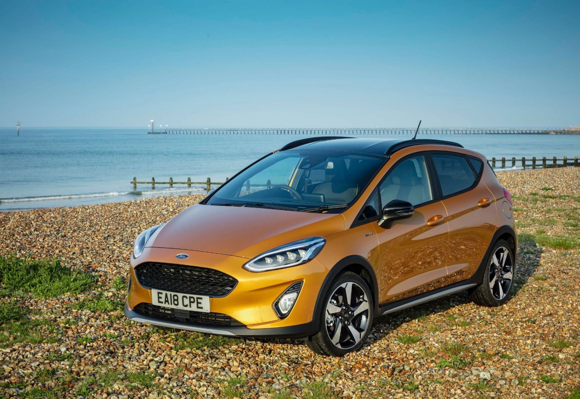 second hand orange ford fiesta car on a rocky beach