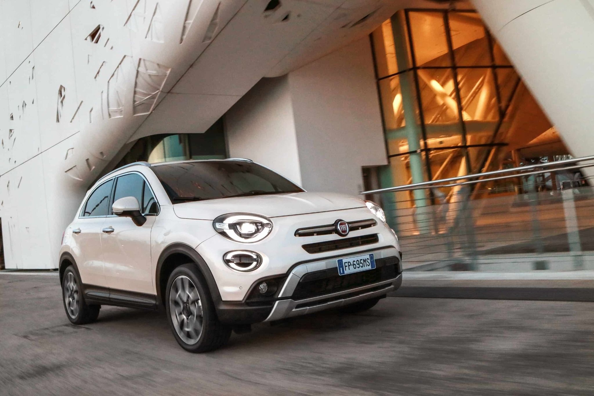 front side view of fiat 500x driving past a building