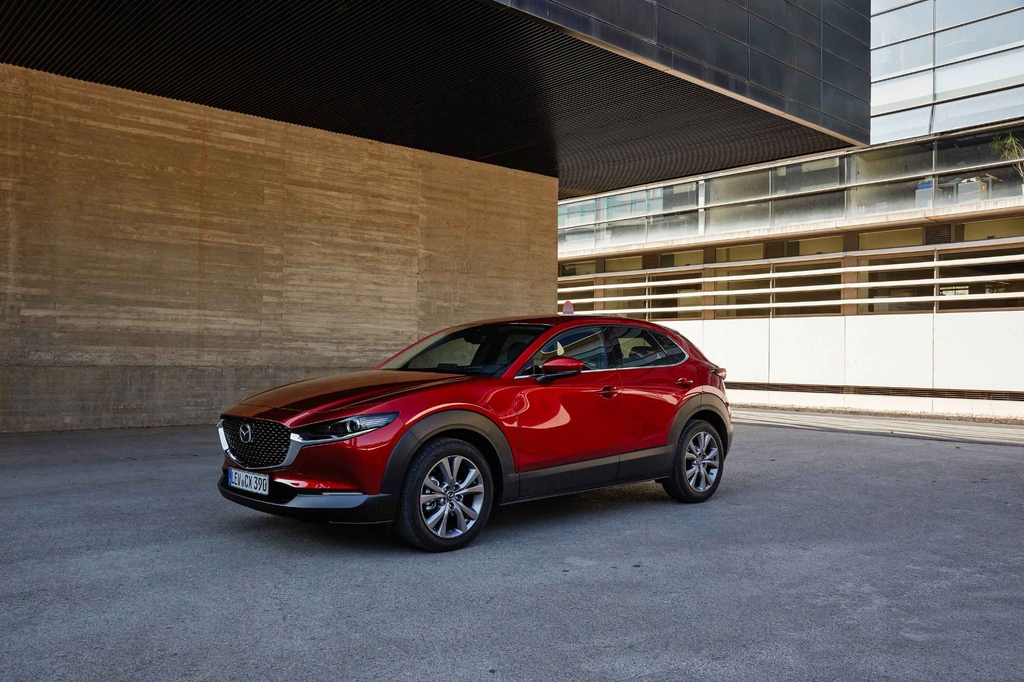 side view of red mazda cx 30 beside a city building