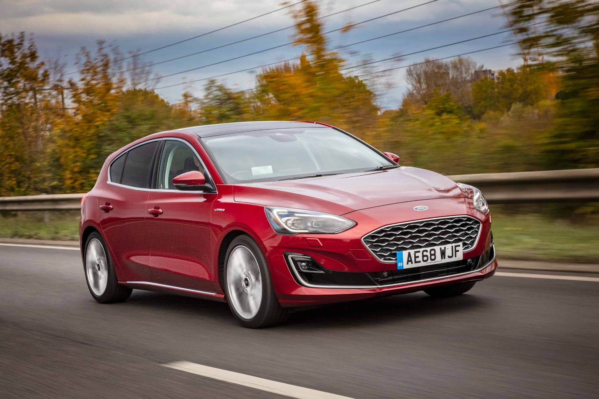 red ford focus vignale side and front view driving down a road