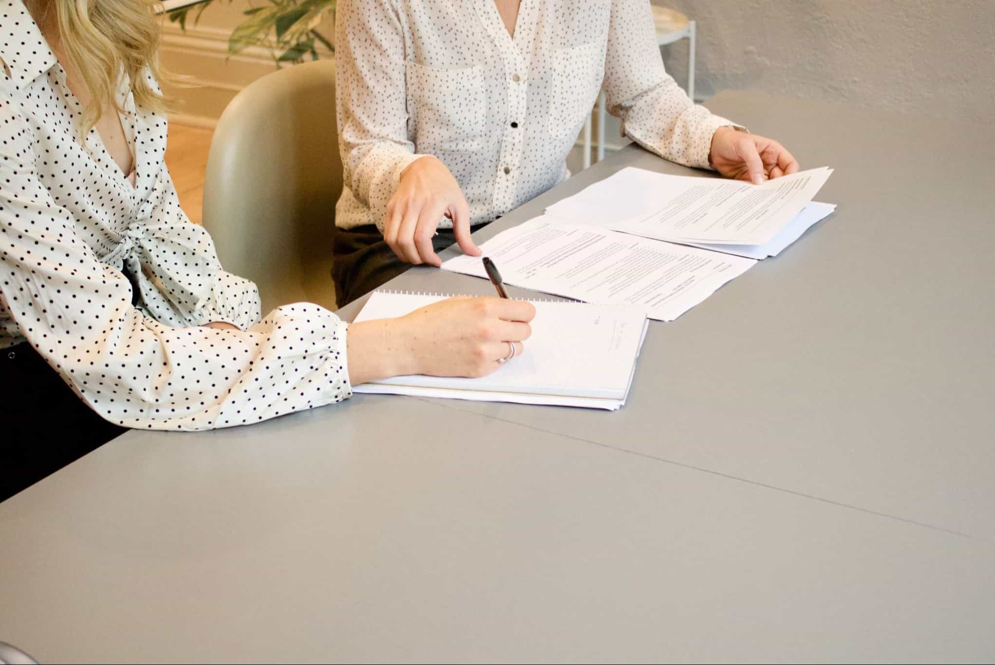two women at a desk looking over paperwork