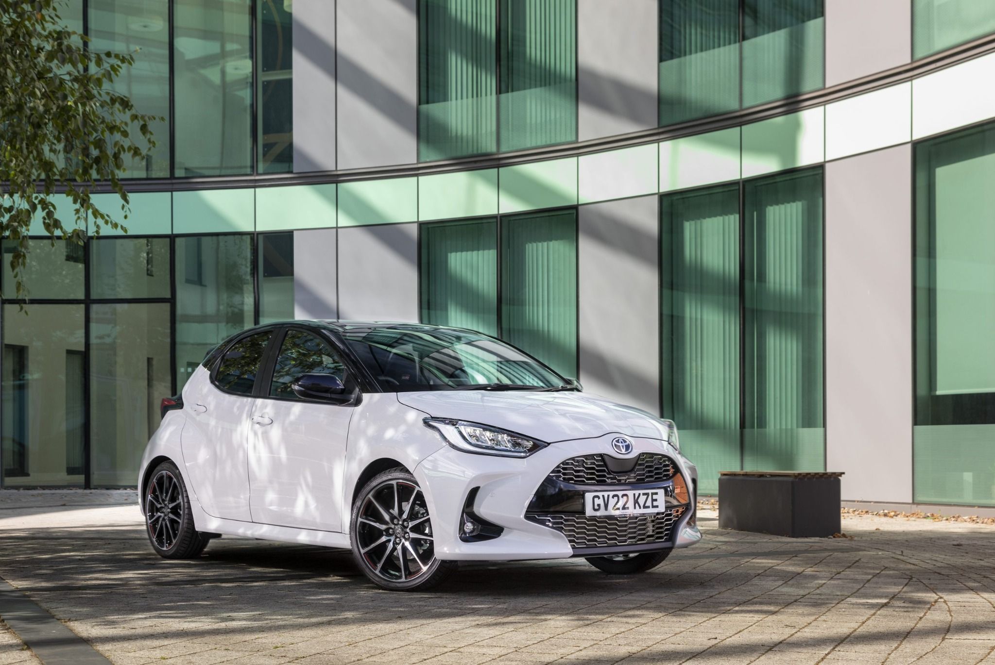 side front view of white toyota yaris in front of building