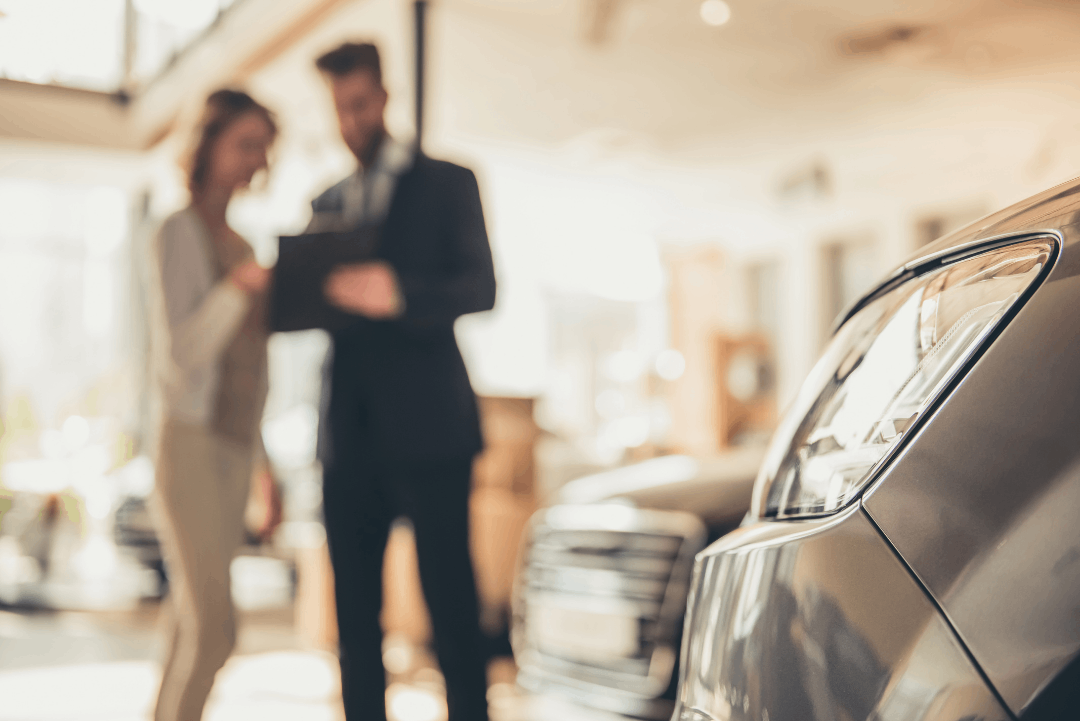 People talking beside car in dealership