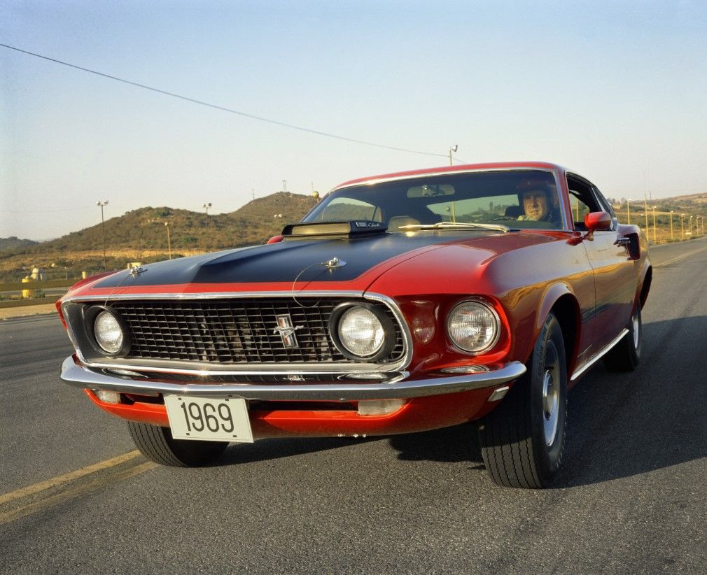 Red Ford Mustang driving down the road