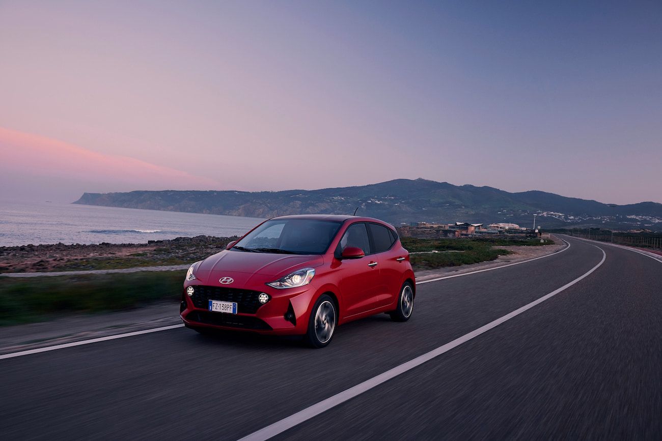 Hyundai-i10-driving-along-a-road-during-sunset-by-the-sea