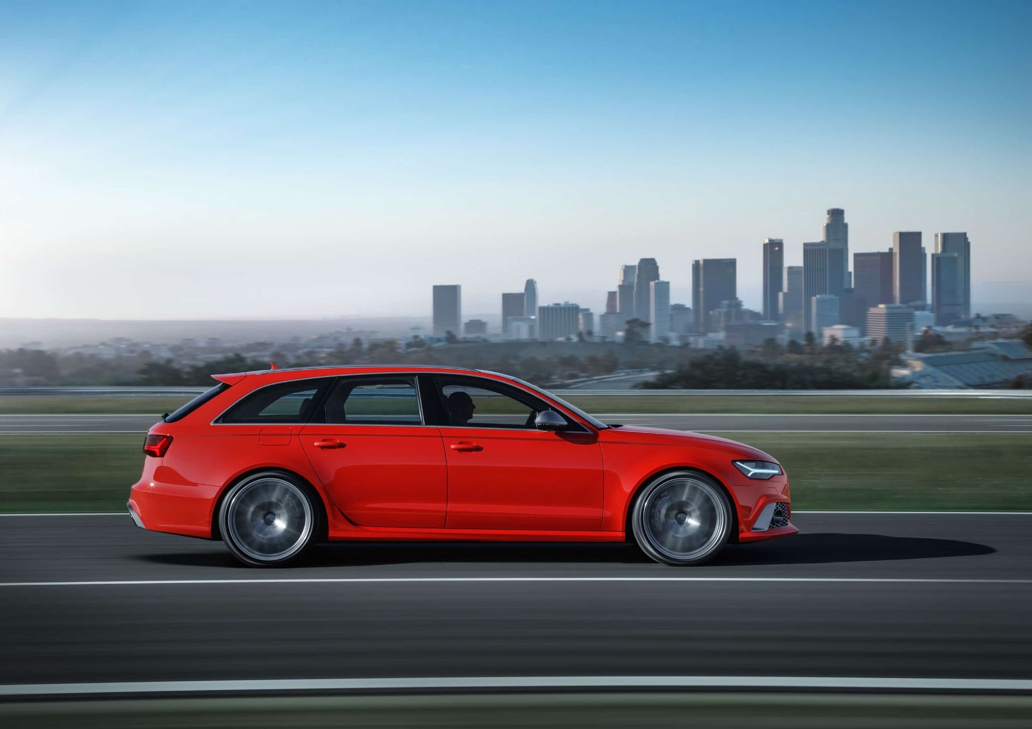 A Side Shot of the Red Audi RS6 Estate Driving in Front of a Cityscape