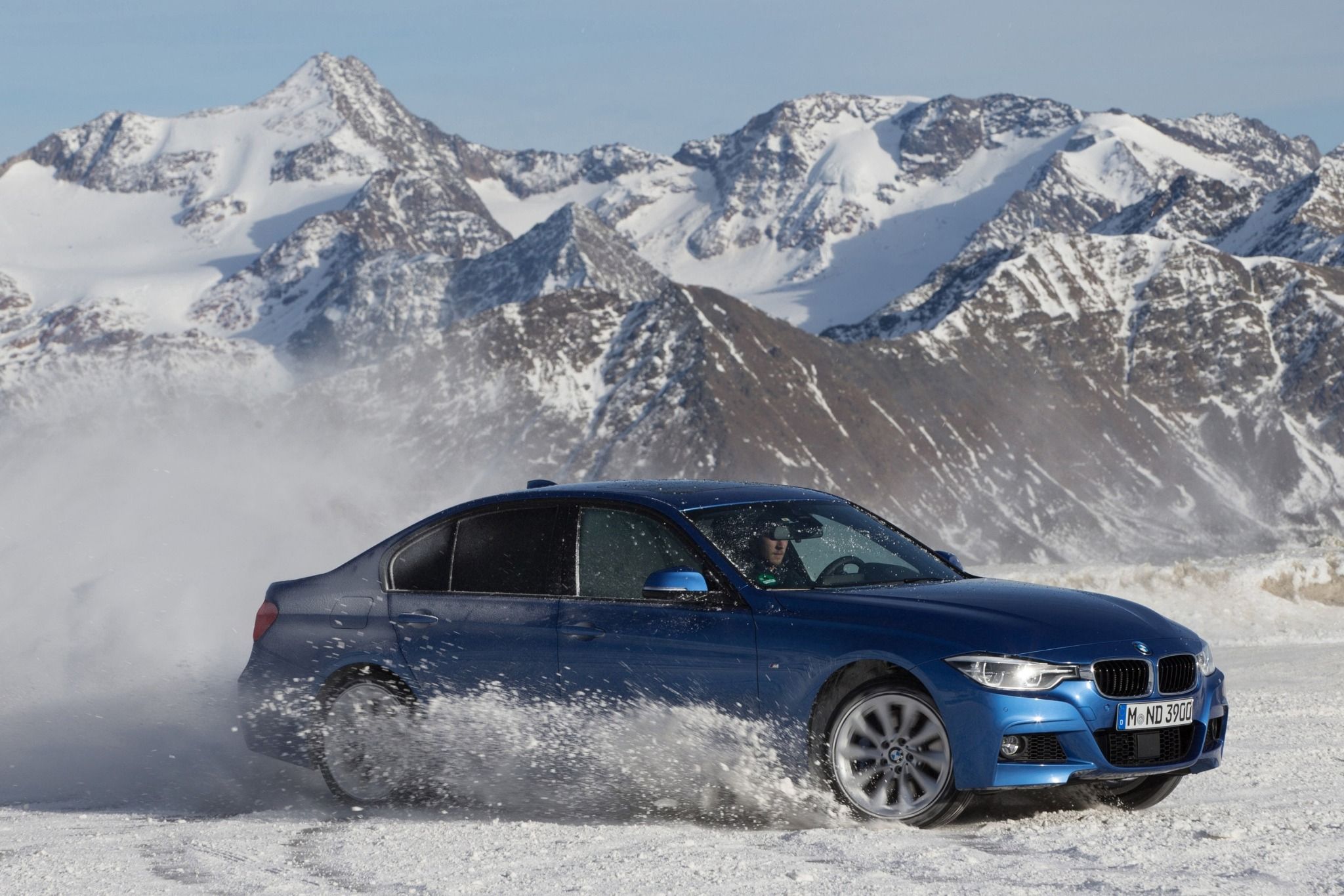 Side view of a Blue BMW driving in snow