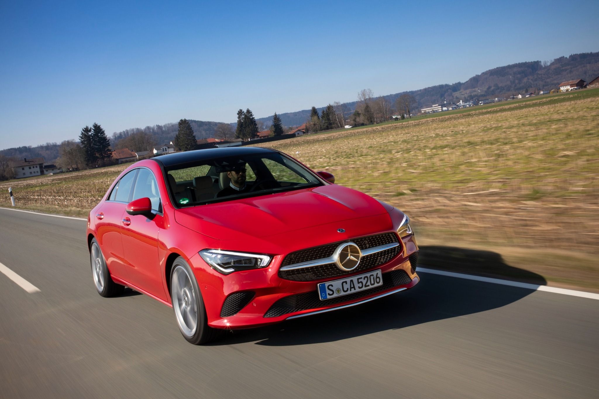 Front view of a red Mercedes CLA driving on a road