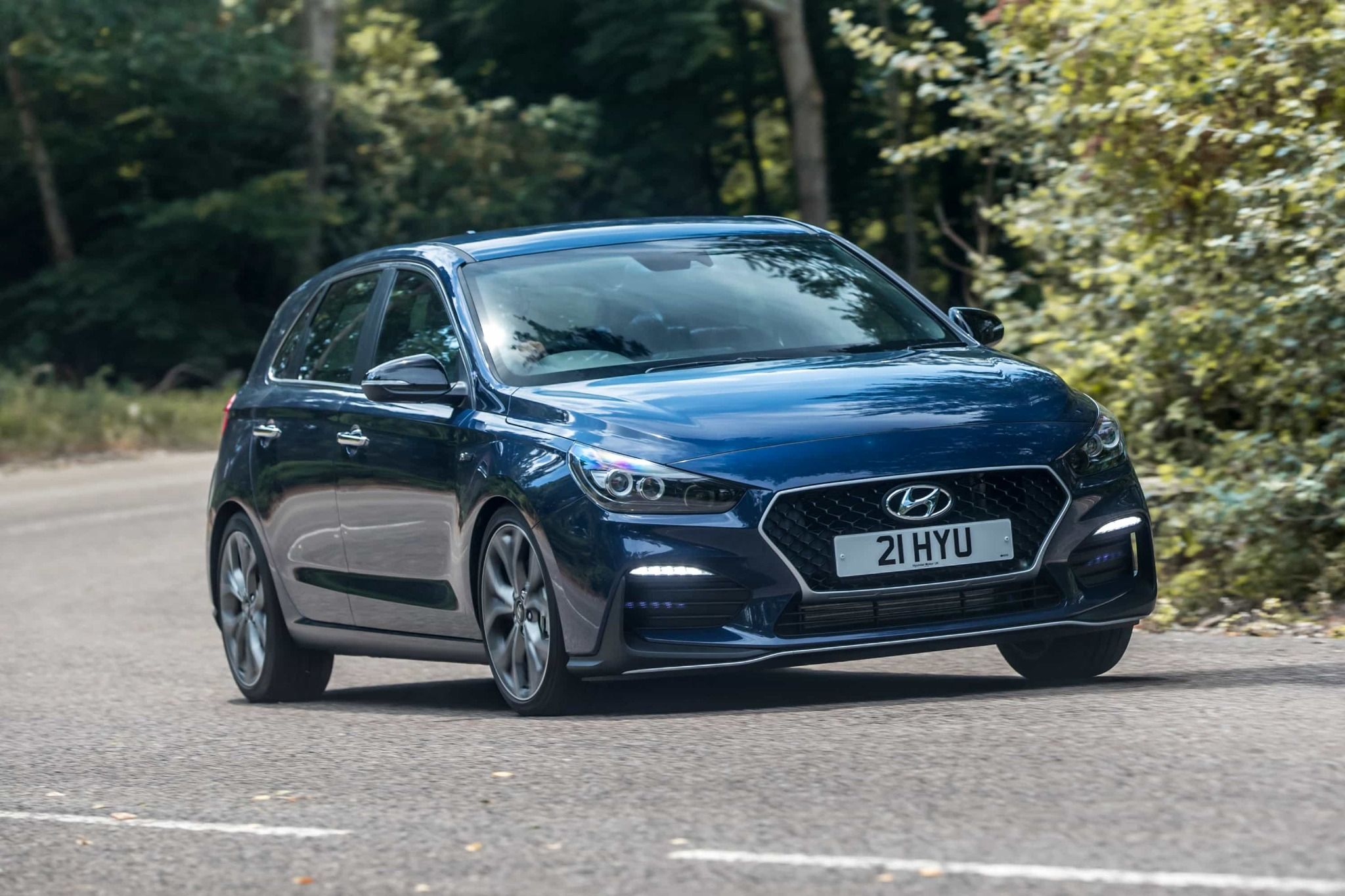 front view of a blue hyundai i30 driving down a road