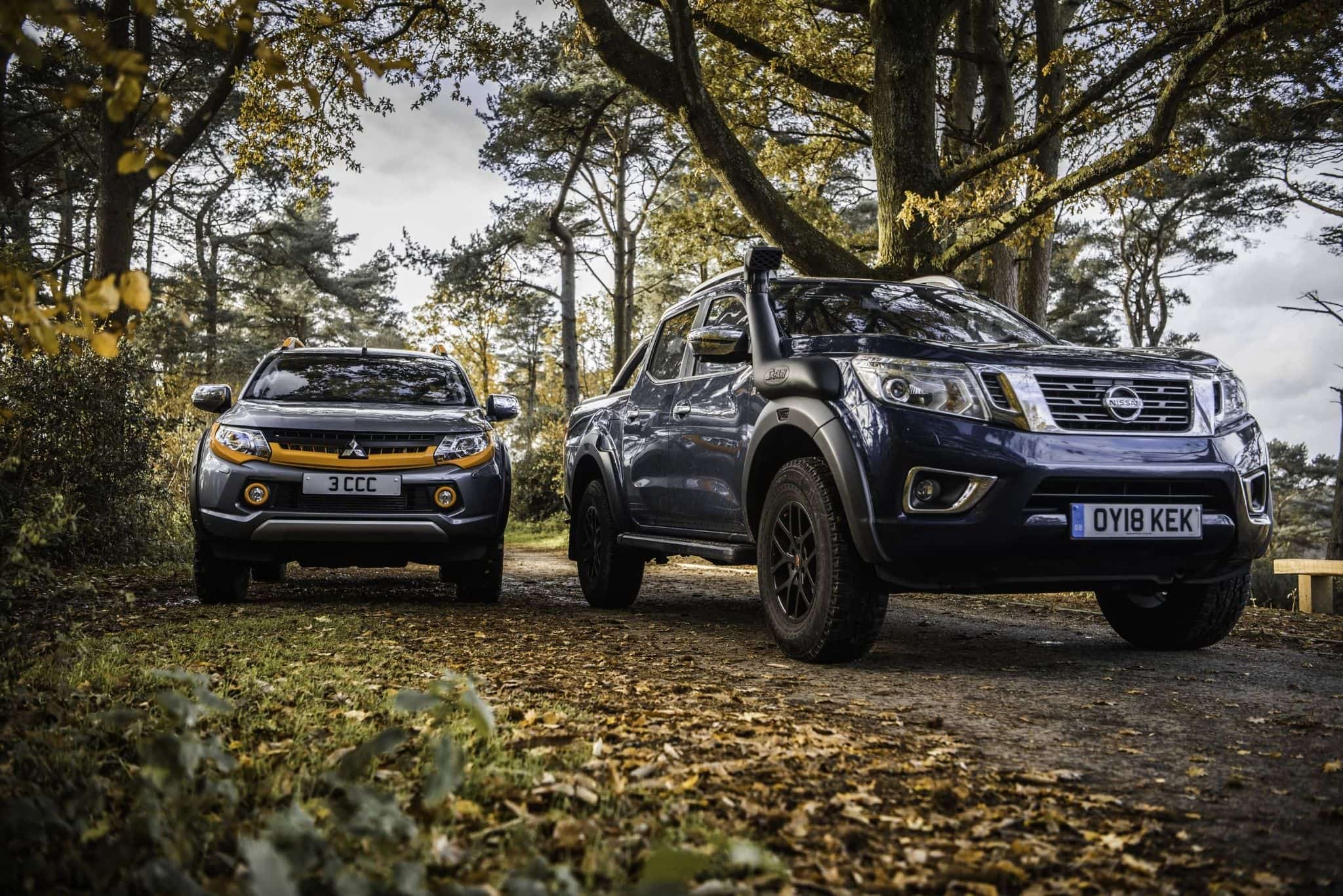 front view of mitsubishi barbarian and nissan navara on a leafy road
