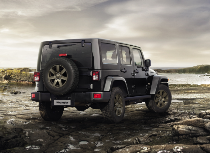 rear view of a black Jeep Wrangler sitting on green rocks