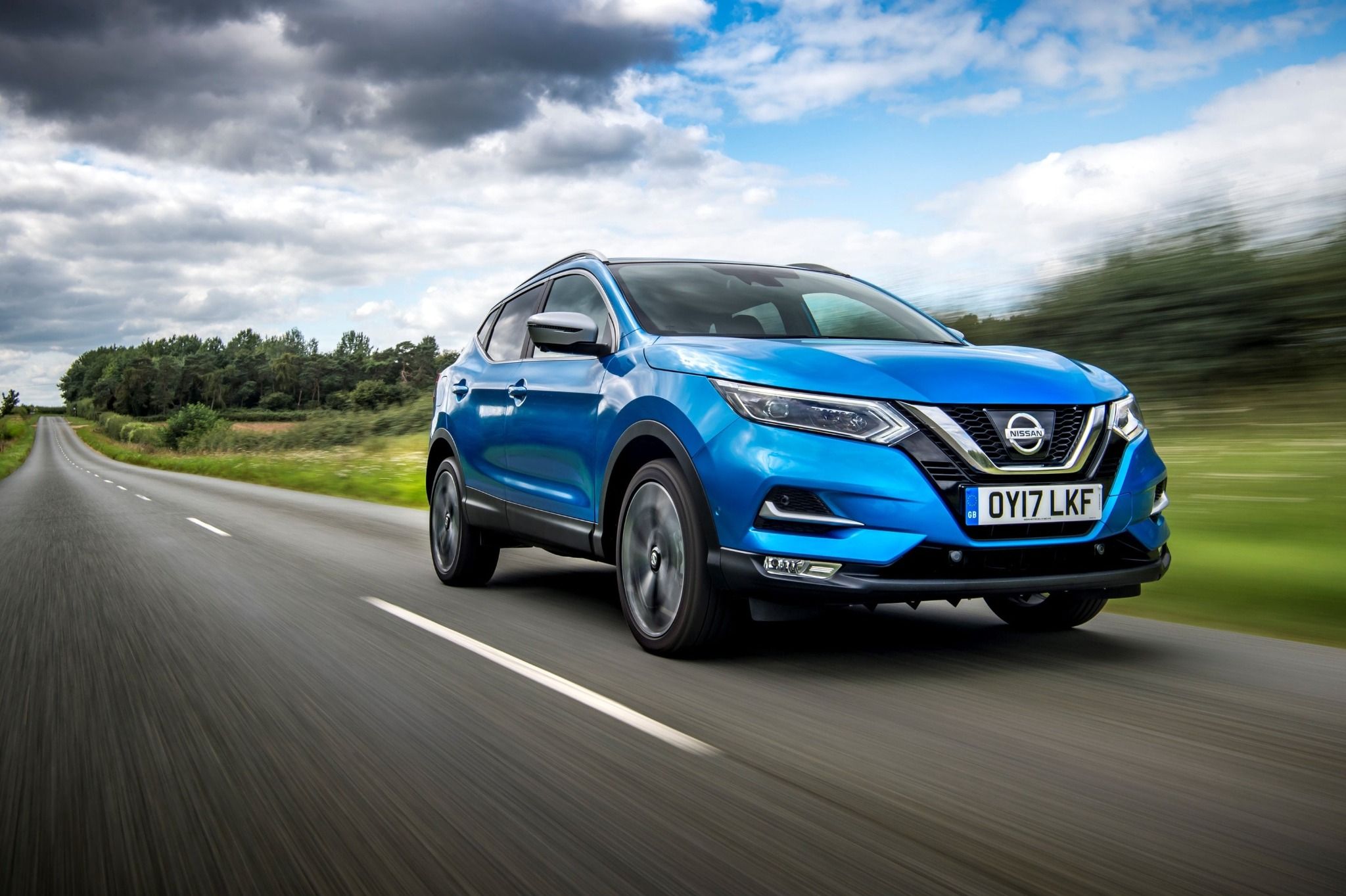 Blue Nissan Qashqai driving down road