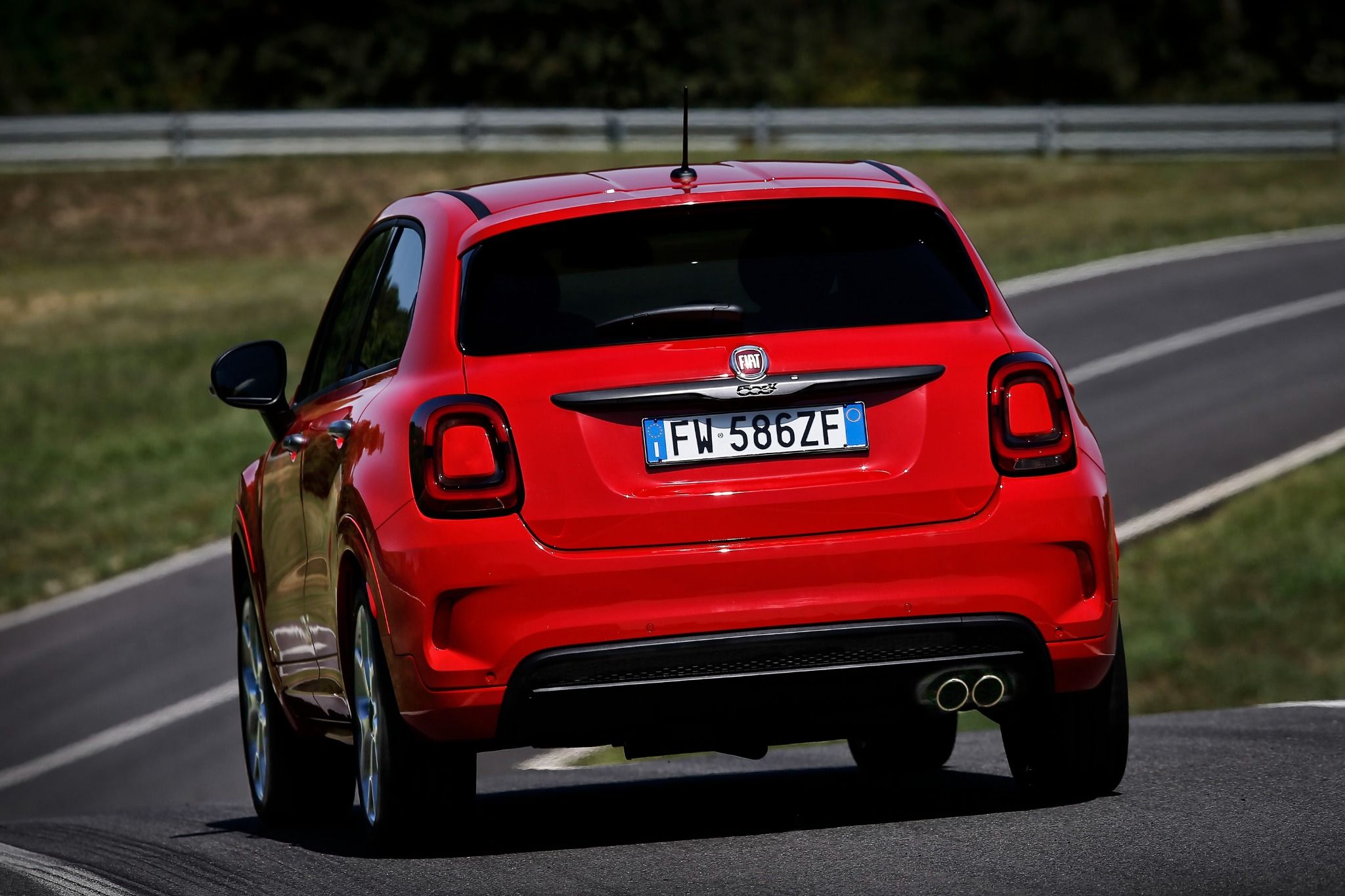 Rear view of red Fiat 500x Sport driving on a road