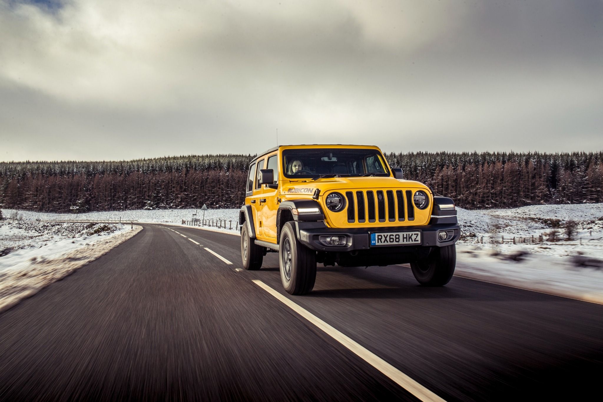 Yellow Jeep Wrangler driving in snow
