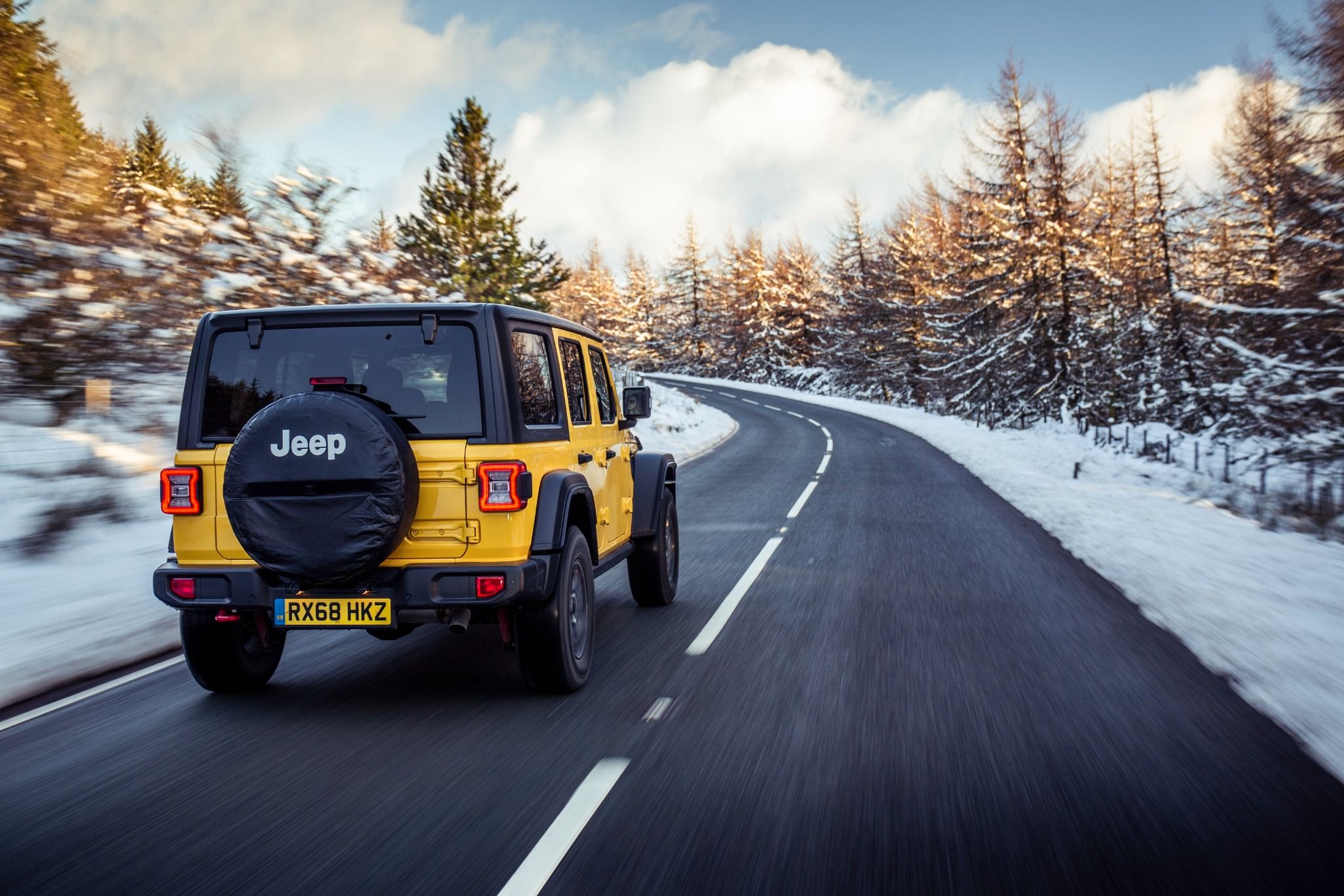 Yellow Jeep Wrangler driving in snow