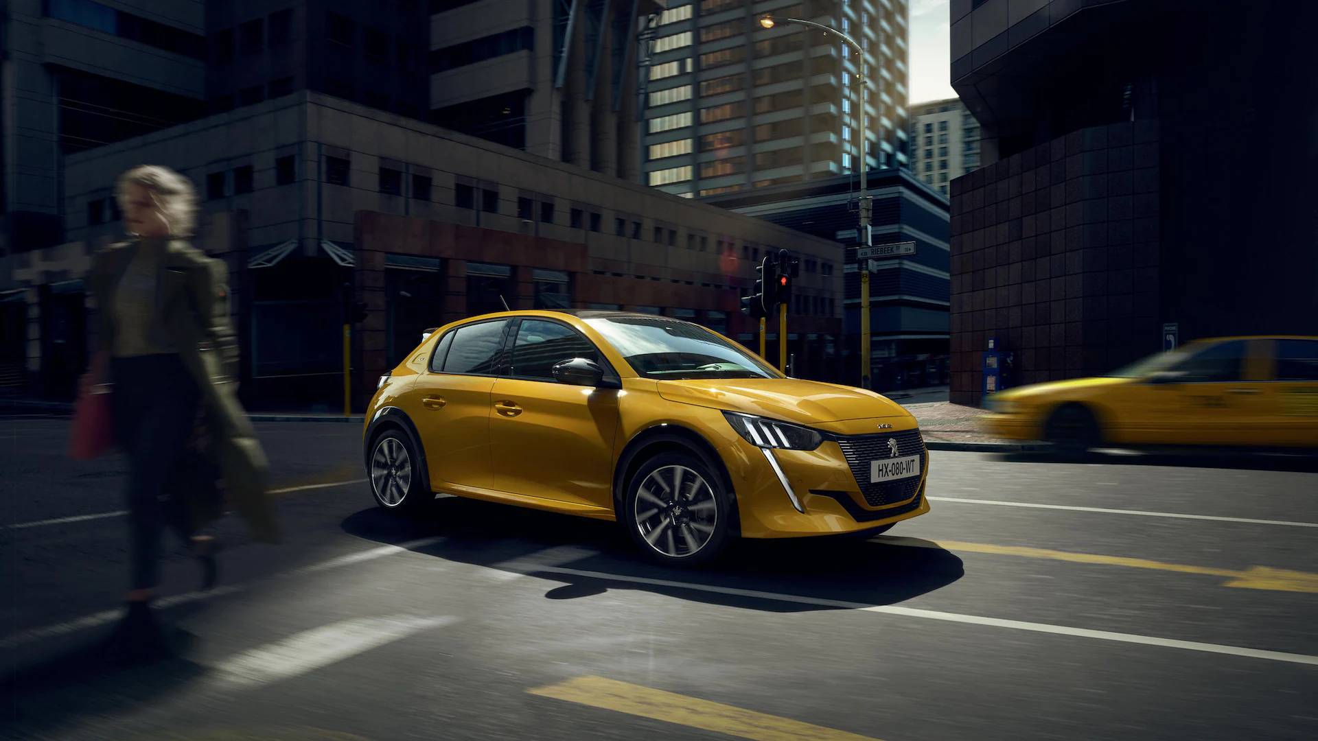 Yellow Peugeot 208 exterior driving down the road
