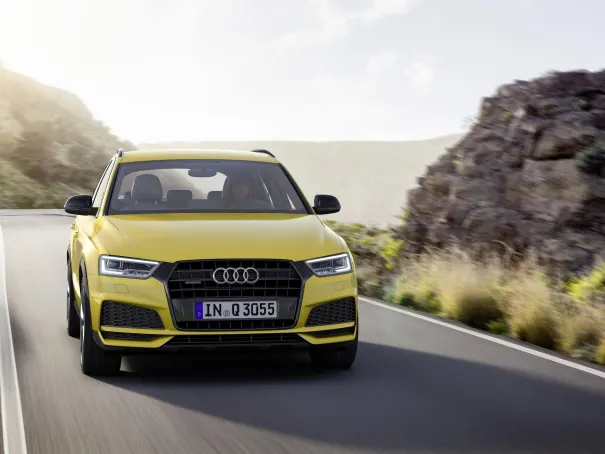 front image of a yellow audi q3 driving down a scenic road
