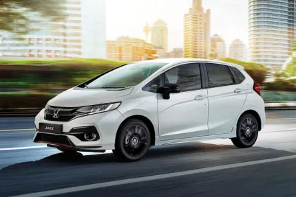 Side view of white honda jazz driving on a road