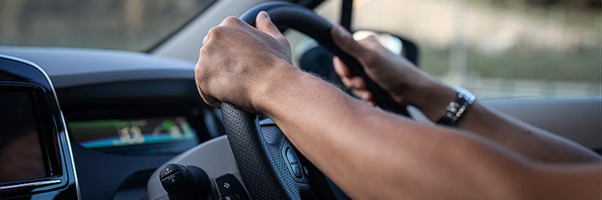 close up of hands gripping onto the top of a steering wheel