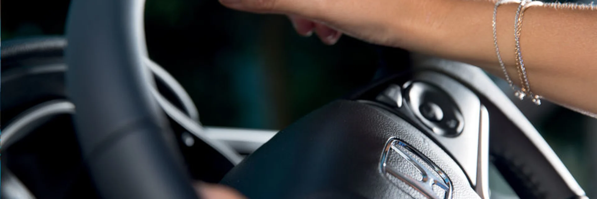 close up of a woman holding onto a honda steering wheel