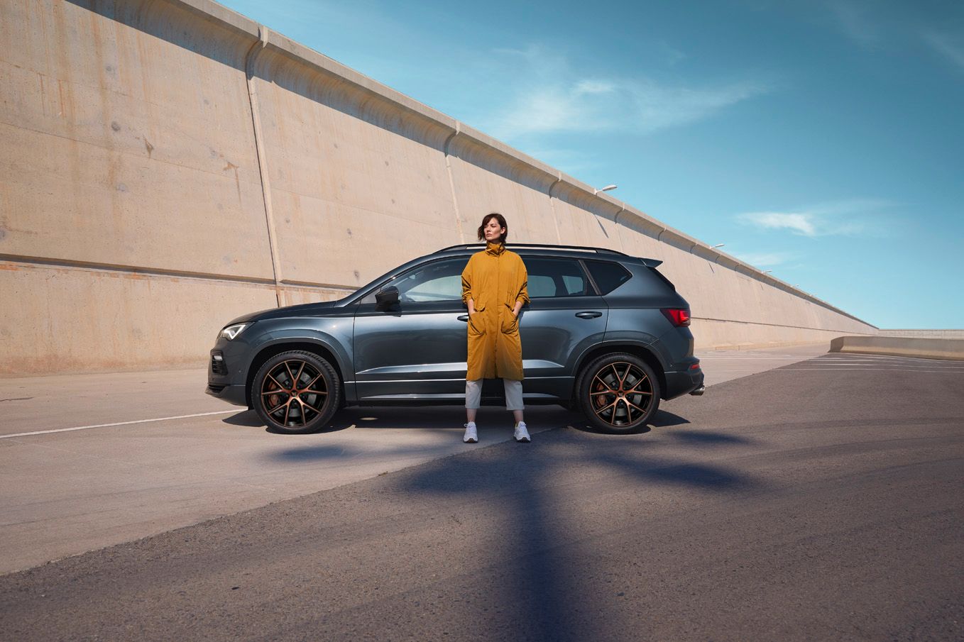 Grey CUPRA Ateca side view with person in yellow coat stood in front of it