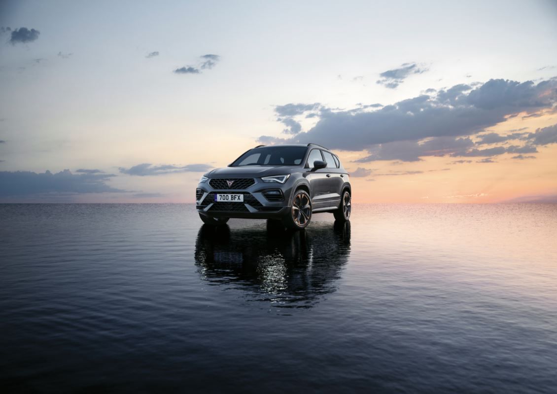 Grey CUPRA Ateca parked on water with a sunset in the background