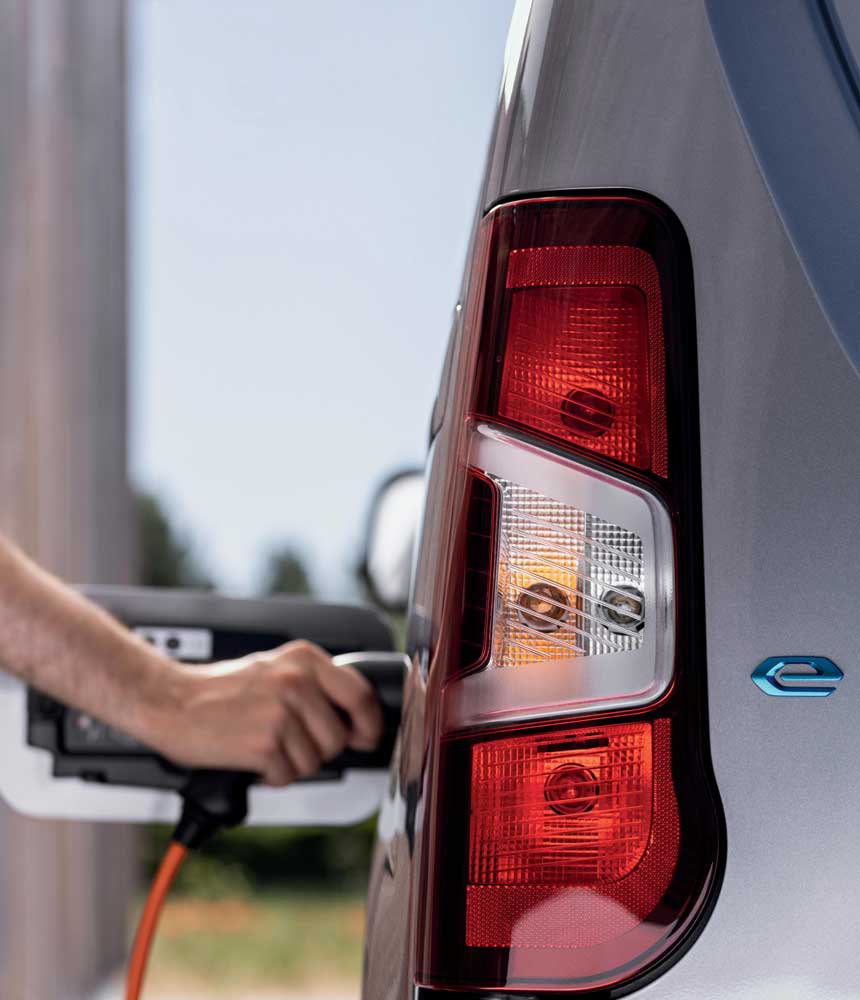 woman connecting a charging cable to a peugeot partner ev