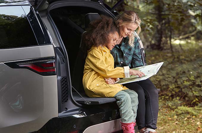 Women and child sitting on the edge of Land Rover Discovery boot