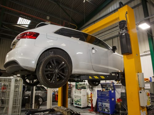 White Audi A3 in the air on a workshop ramp