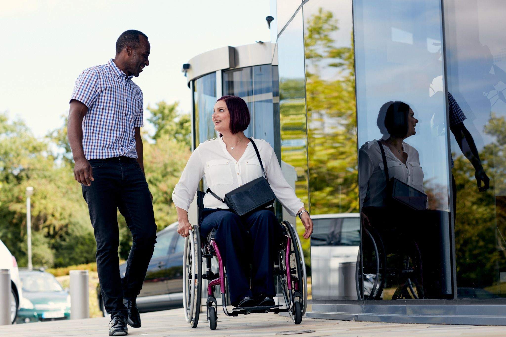 man walking with woman in wheelchair next to dealership