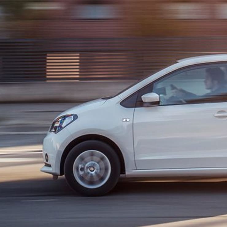 Side view of a white SEAT Mii driving on a road