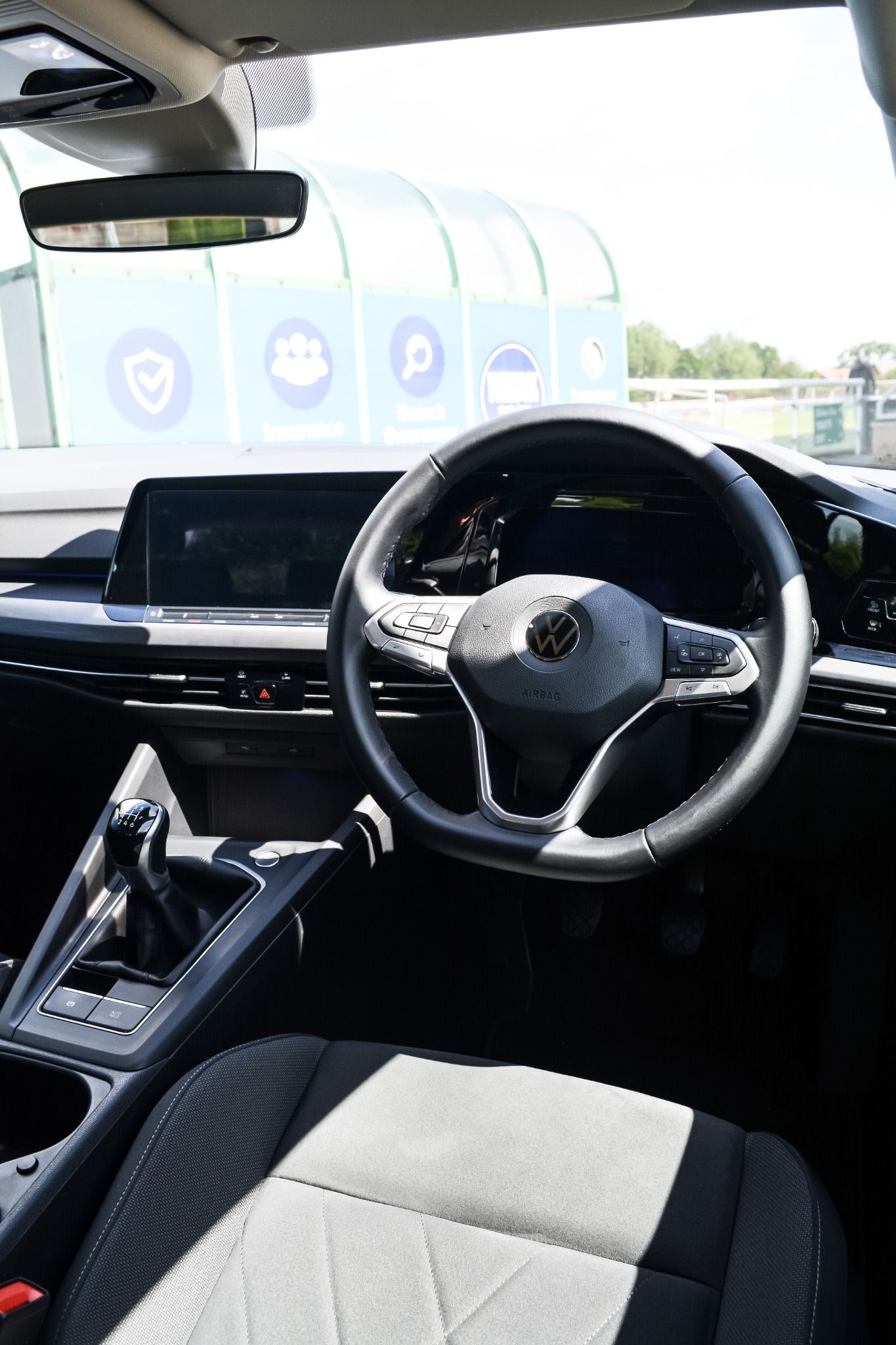 Interior view of Volkswagen Golf showing cloth seats, leather steering wheel, gear stick and infotainment system