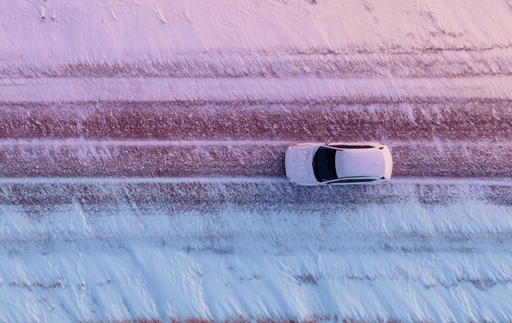 Birds eye view of car driving down a snowy road