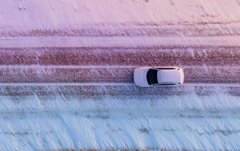 top view of a white car driving on a snowy road