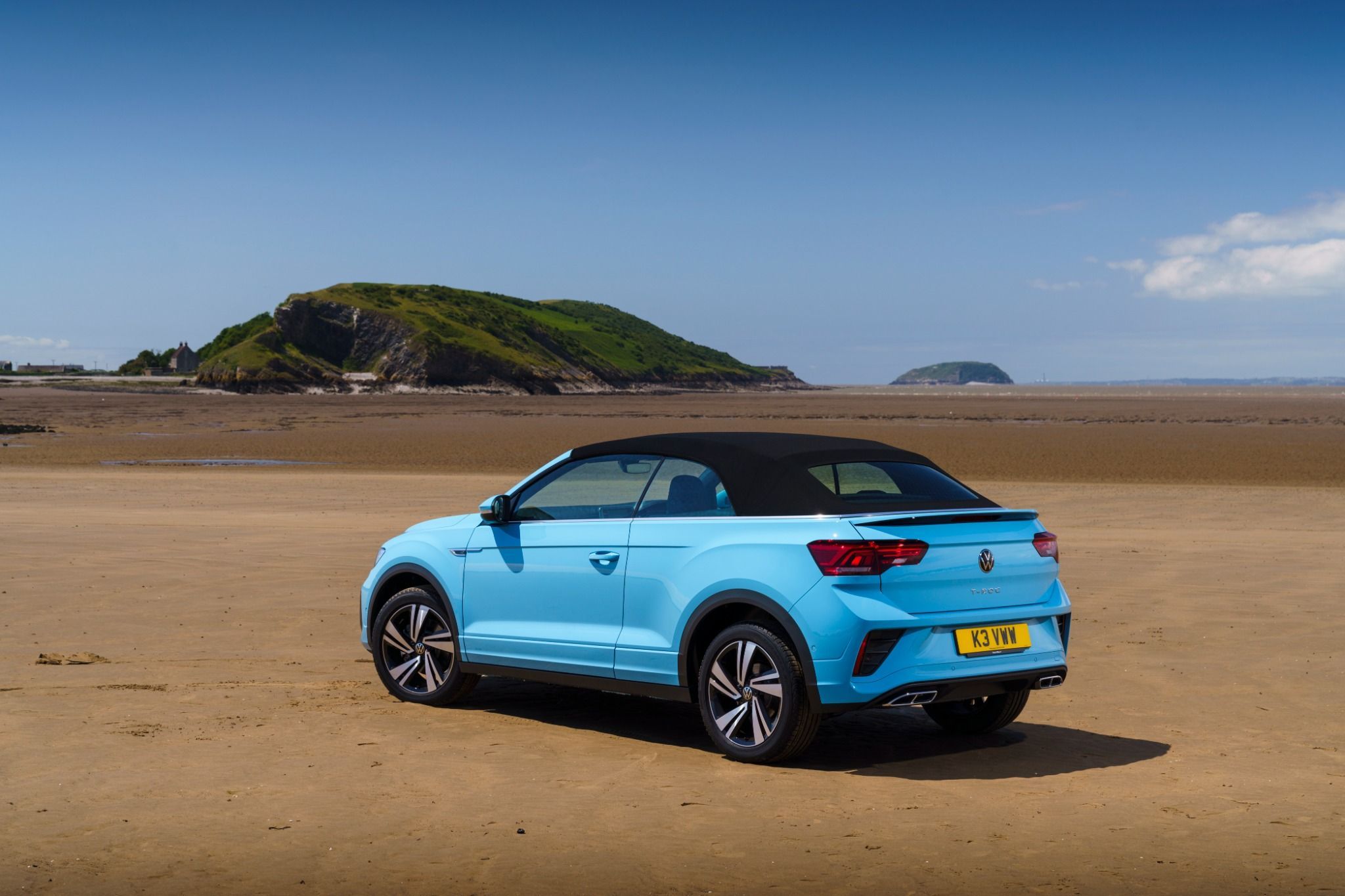 Blue VW T-Roc Cabriolet parked on sand with the roof up