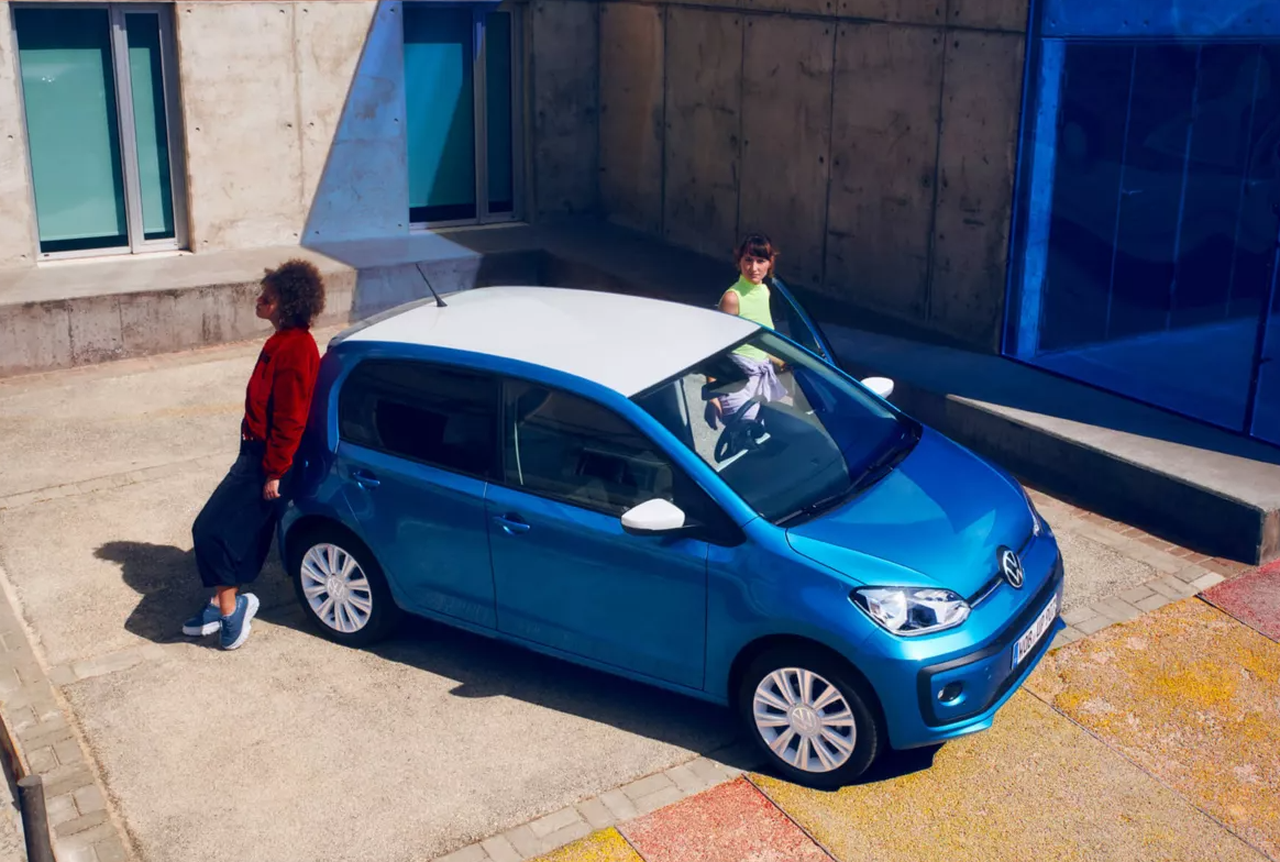 Blue Volkswagen up with people standing next to it