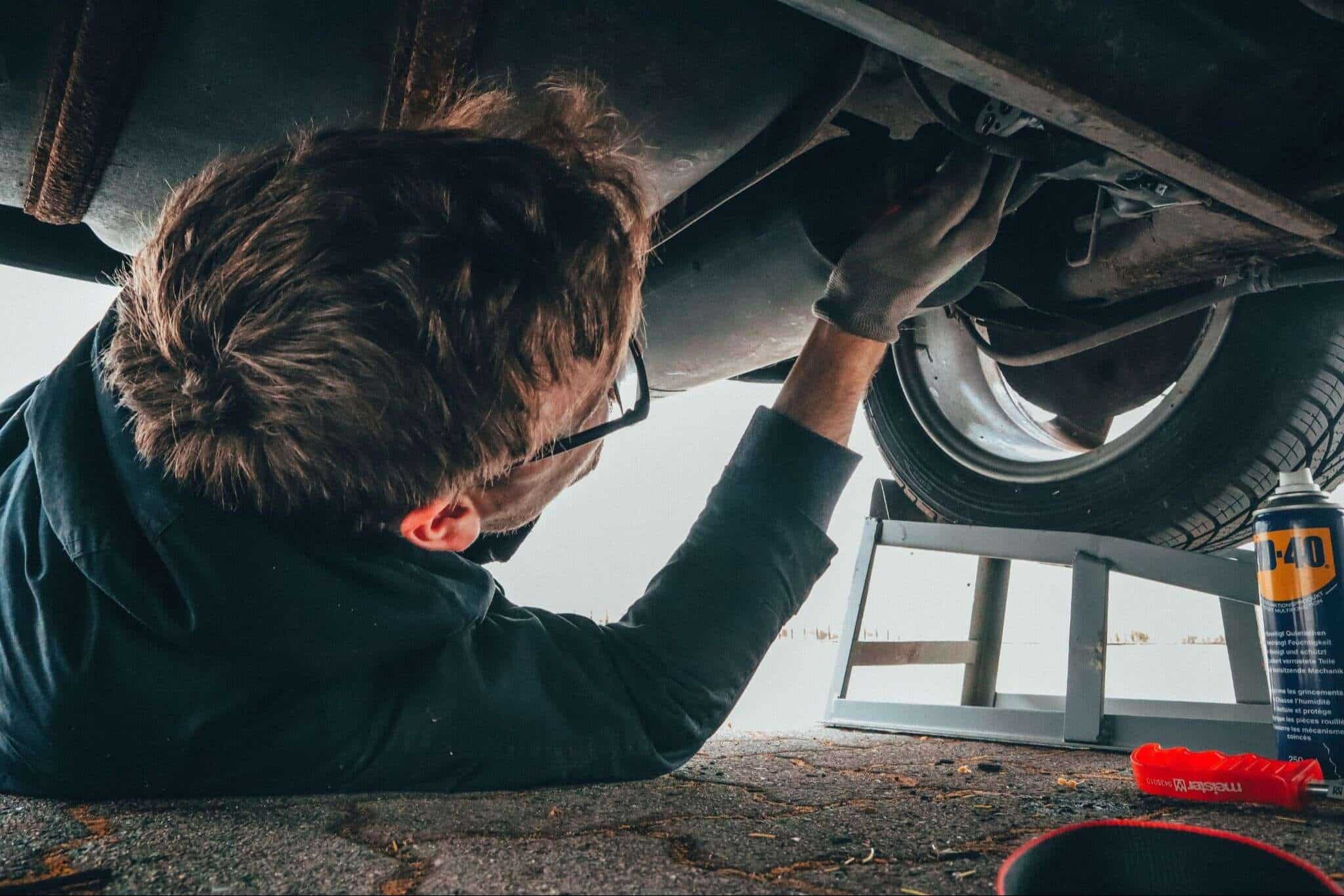 Garage man looking under the bottom side of a car