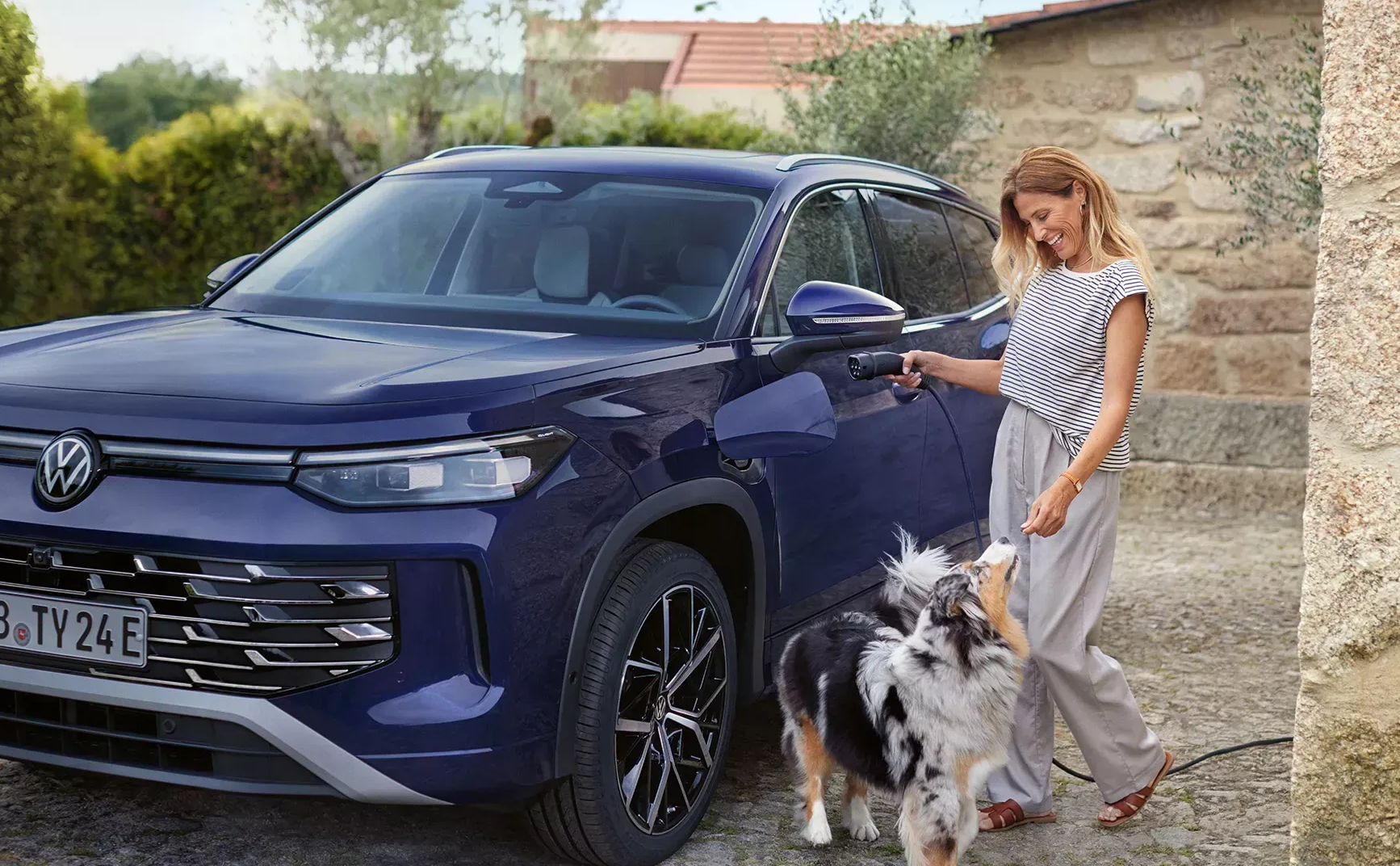 Woman with dog going to charge Volkswagen Tayron