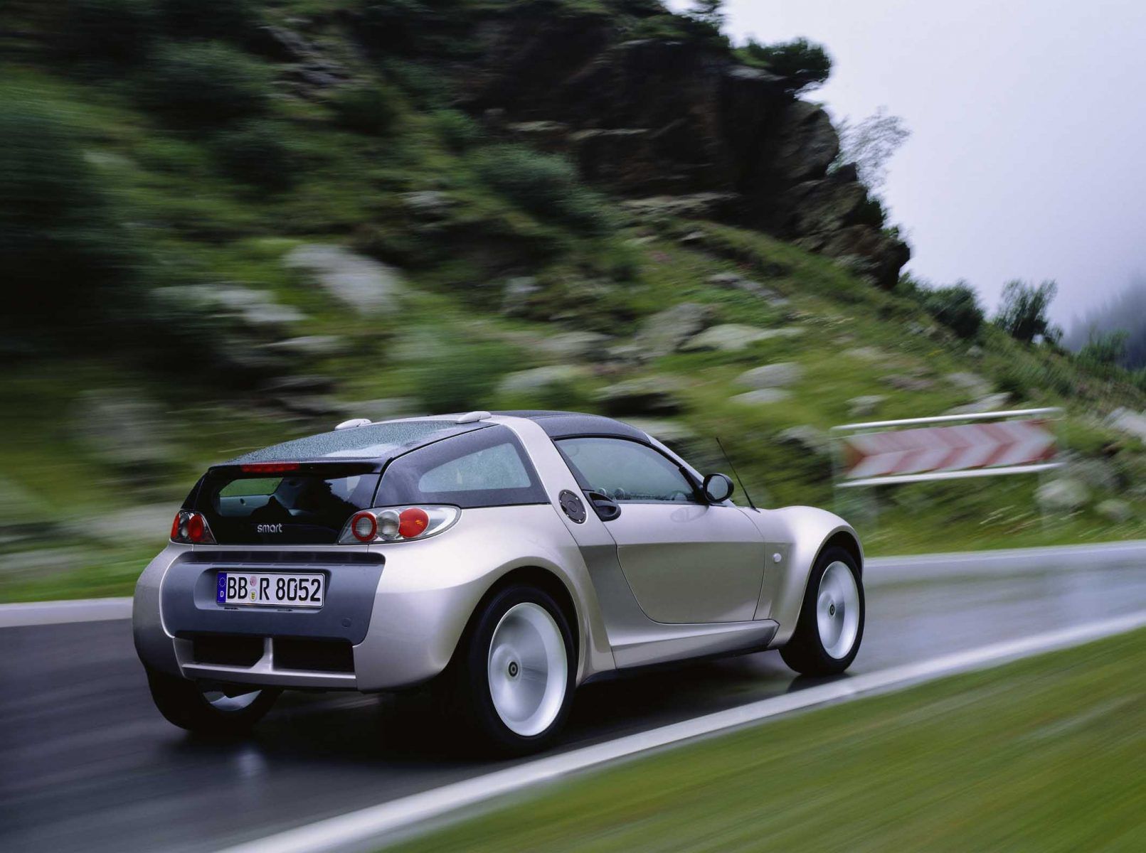 Rear view of a silver Smart Roadster driving on a road