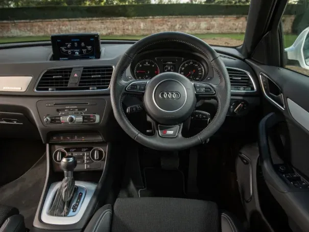 interior view of a right hand drive audi q3 showing steering wheel, driver display and centre console