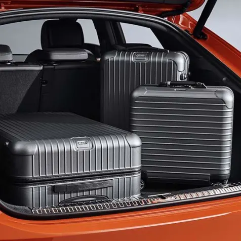 close up of the boot space of an orange audi q3 sportback. The boot contains three suitcases.