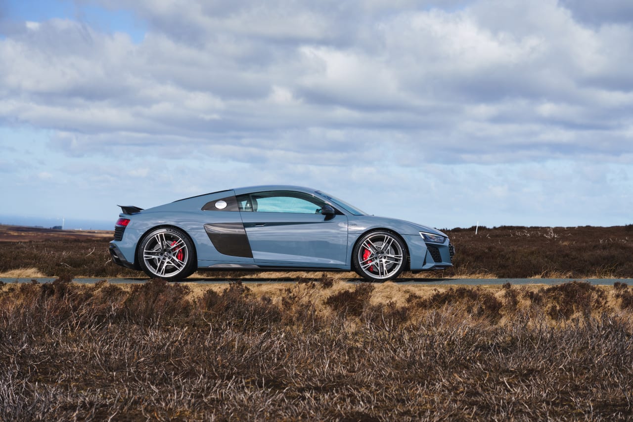 Grey Audi R8 Coupe exterior side parked by countryside road