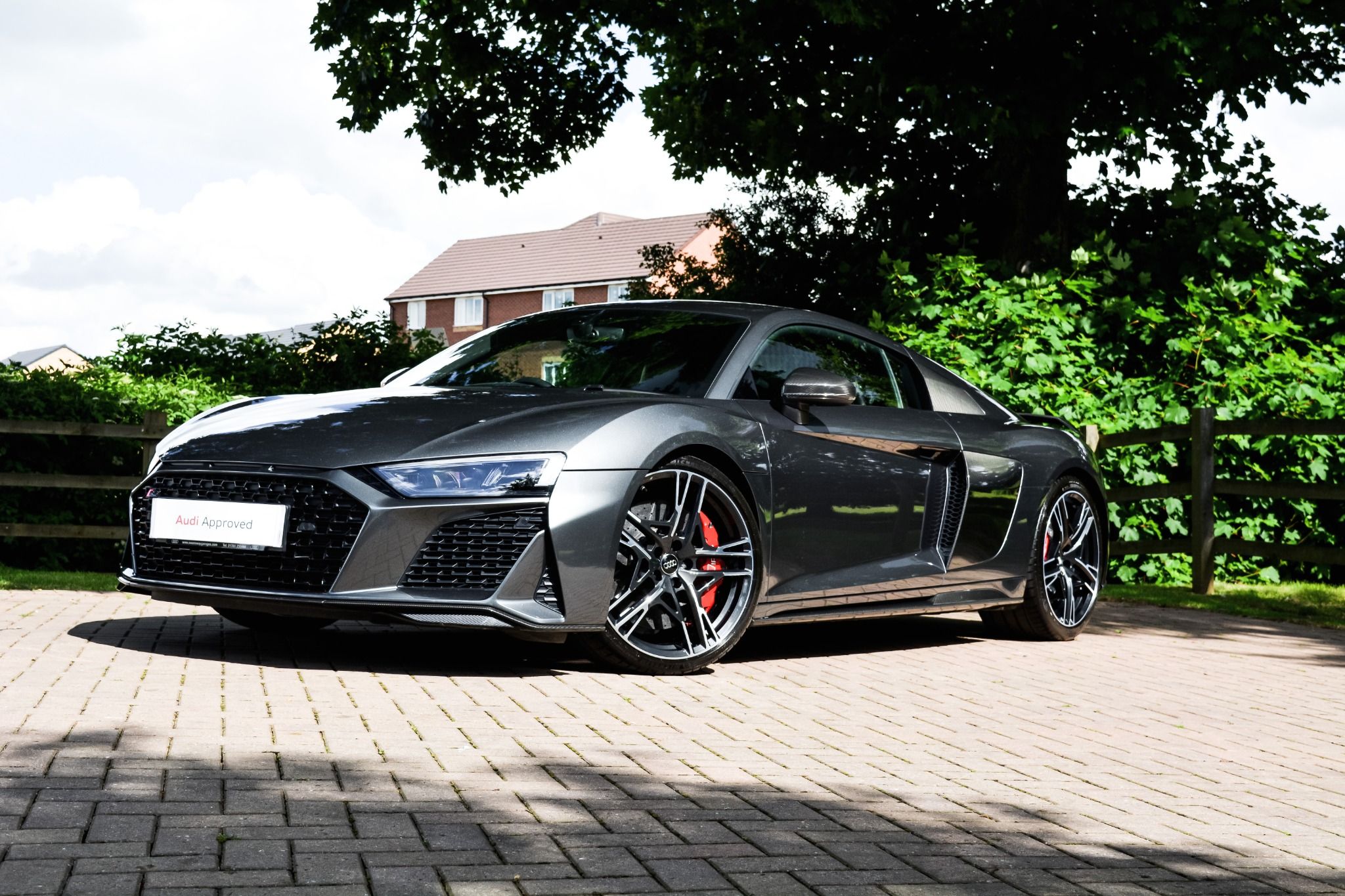 All black Audi R8 with red brake pads parked underneath tree